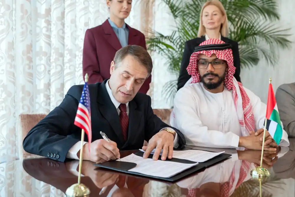 
A group of people sitting by table while one of them signing
